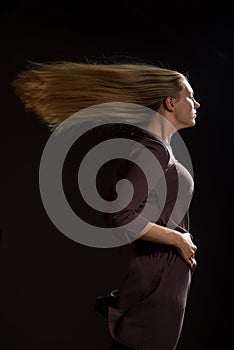 Caucasian white female model portrait. The wind blowing the long blonde hair off on beautiful girl. Woman posing studio shot