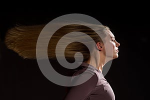 Caucasian white female model portrait. The wind blowing the long blonde hair off on beautiful girl. Woman posing studio shot