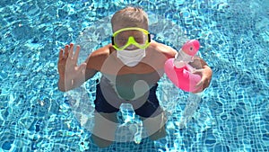 Caucasian white male in swimming pool with a toy flamingo in a medical face mask