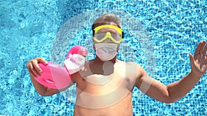 Caucasian white male in swimming pool with a toy flamingo in a medical face mask