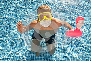 Caucasian white male in swimming pool with a toy flamingo in a medical face mask