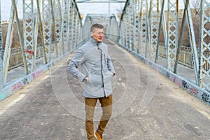 Caucasian white man with a gray coat on the bridge