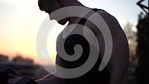 Caucasian white muscular man lifting dumbbells against the sunset sky background. Concept of willpower, motivation and