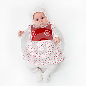 Caucasian White newborn baby girl in a dress with ruffles on a pink background with a flowers bandage on her head.