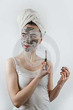 caucasian woman applying clay mask with brush on her face, skin care