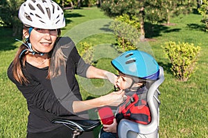 Caucasian woman and baby boy on a bicycle with biking helmets.