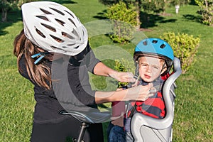 Caucasian woman and baby boy on a bicycle with biking helmets.