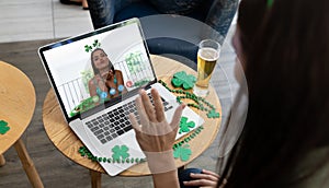 Caucasian woman at bar making st patrick's day video call waving to friend blowing kiss on laptop