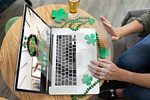Caucasian woman at bar making st patrick's day video call waving to friend in costume on laptop