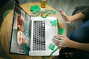 Caucasian woman at bar making st patrick's day video call waving to male friend on laptop