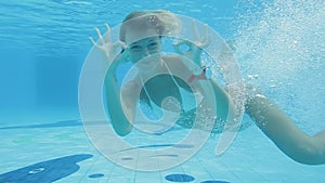 Caucasian woman in bikini swimming underwater in swimming pool.
