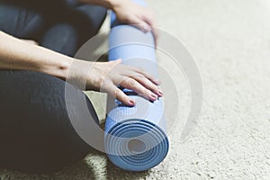 Caucasian woman in black clothes sitting on bege carpet rolling