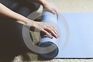 Caucasian woman in black clothes sitting on bege carpet rolling