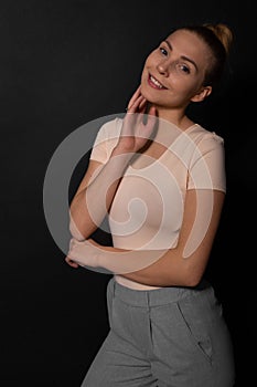 Caucasian woman with blond bunched hair looks at camera, smiling. Hand at chin