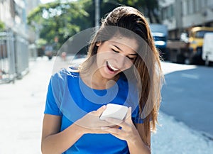 Caucasian woman in blue shirt surfing the web with phone