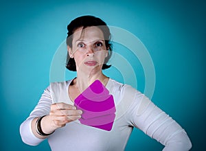 Caucasian Woman with brown hair holding purple cards on light blue background.