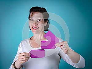 Caucasian Woman with brown hair holding purple cards on light blue background.