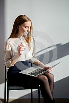 Caucasian woman in business clothes sitting on chair with laptop computer