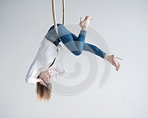 Caucasian woman in casual clothes on an aerial hoop.