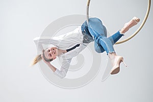 Caucasian woman in casual clothes on an aerial hoop.