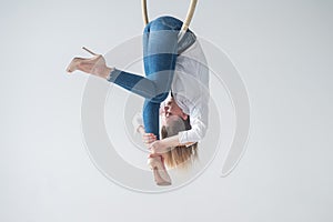 Caucasian woman in casual clothes on an aerial hoop.