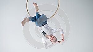 Caucasian woman in casual clothes on an aerial hoop.