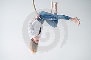 Caucasian woman in casual clothes on an aerial hoop.