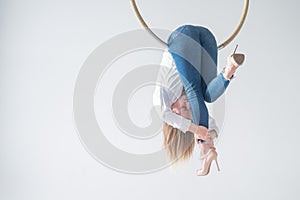 Caucasian woman in casual clothes on an aerial hoop.