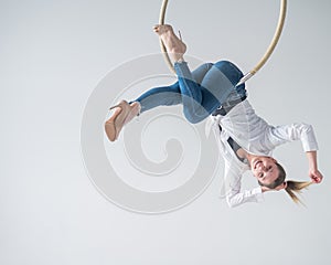 Caucasian woman in casual clothes on an aerial hoop.