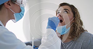 Caucasian woman and caucasian female doctor wearing face mask at home using swab test