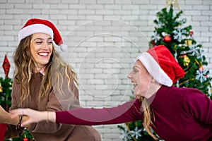 Caucasian woman celebrating holiday festival  with Christmas tree and gift box with friend