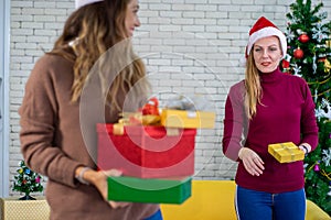 Caucasian woman celebrating holiday festival with Christmas tree and gift box with friend