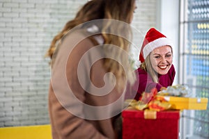 Caucasian woman celebrating holiday festival with Christmas tree and gift box with friend