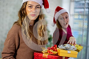 Caucasian woman celebrating holiday festival with Christmas tree and gift box with friend