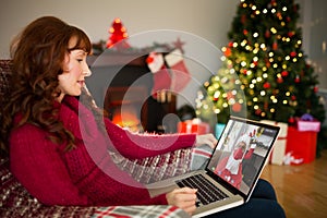 Caucasian woman on christmas laptop video call caucasian santa wearing face mask