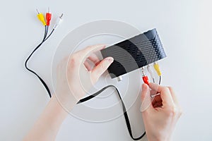 Caucasian woman connect an analog cable to the jack on black digital television set-top box