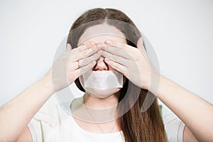 Caucasian woman covering her eyes with hands while mouth sealed with tape