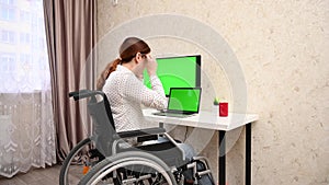 Caucasian woman with disabilities working at the computer while sitting in a wheelchair.