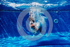 Caucasian woman diving in swimming pool wearing white dress.underwater view. Summer time and vacation concept