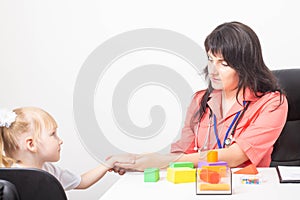 A caucasian woman doctor holds the hand of a little girl patient 3-4 years old in the doctor s office of a pediatrician. Children