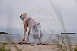 Caucasian woman doing camel pose Ustrasana asana exercise outdoors.