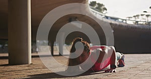 Caucasian woman doing push-ups under a bridge