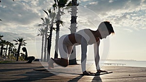 Caucasian woman doing yoga asana in the beach. Young Female wearing sport clothes in lotus pose with defocused