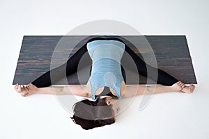 Caucasian woman doing yoga splits upavistha konasana on fitness mat.