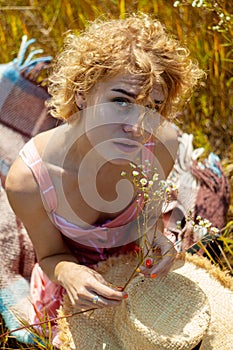 Caucasian Woman In Dress with curly hair Enjoing Wildflowers In Summer Field