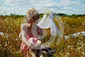 Caucasian Woman In Dress with curly hair Enjoing Wildflowers In Summer Field