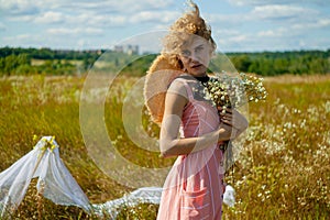 Caucasian Woman In Dress with curly hair Enjoing Wildflowers In Summer Field