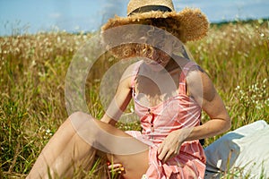 Caucasian Woman In Dress with curly hair Enjoing Wildflowers In Summer Field