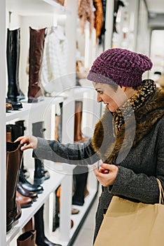 Caucasian woman dressed in warm clothing shopping for shoes