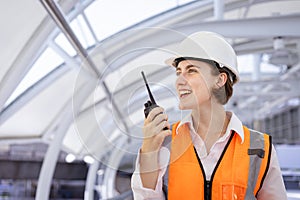 Caucasian woman engineer is using walkie talkie while inspecting the construction project for modern architecture and real estate